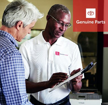Helpful technician reviewing parts order on clipboard with customer.
